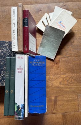 several books on a wooden table with a cat laying on top of them