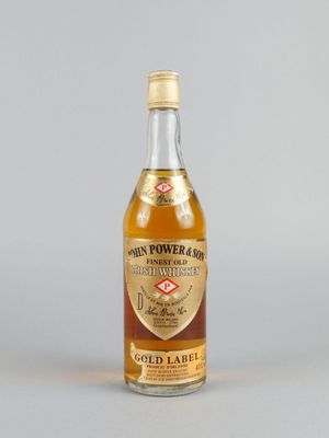 une image représentant une bouteille d'alcool à l'étiquette dorée posée sur une surface grise