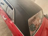 a red car with a black top parked in a garage