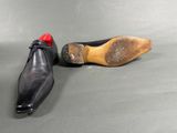 pair of black leather shoes with red soles on a grey surface