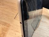 a broken cell phone sitting on a table with a broken screen