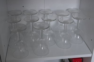 de nombreux verres à vin vides posés sur une étagère dans un placard