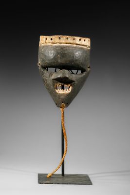 un masque en bois posé sur un socle, entouré d'une corde