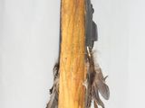 a wooden stick with feathers hanging from it ' s side