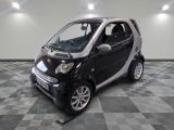 une petite Smart noire et blanche posée sur un sol à damier