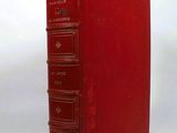 an old red book sitting on top of a white table