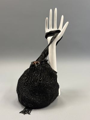 sac orné de perles noires, sur lequel figure une main tenant un couteau et une fourchette