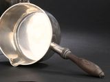 une coupe en argent avec un manche en bois sur un fond noir