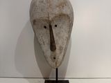 a sculpture of a mask on a stand on a white surface