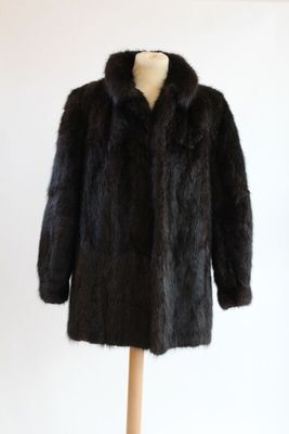 un manteau de fourrure noir posé sur un mannequin, devant un mur blanc
