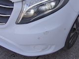the front end of a white car with a dent in it ' s bumper