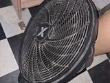 une personne debout à côté d'un ventilateur, sur un sol à damier