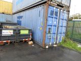 a dumpster next to a blue container on the side of the road