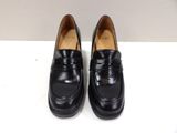 a pair of black loafers on a white surface