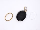 two gold rings and a black oval pendant on a white surface