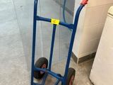 un diable bleu avec une poignée rouge posé par terre