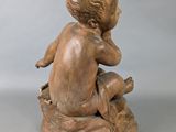 statue of a boy sitting on a rock with his hands on his knees