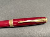 a red pen with gold trim sitting on a table