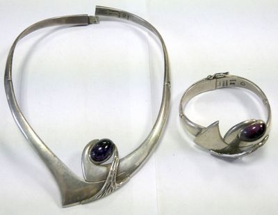 a silver necklace and ring with a purple stone on it