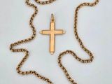 a gold cross pendant on a chain with a chain around it