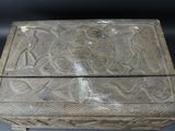 an old wooden box with carvings on it sitting on a table