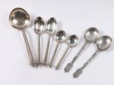 six silver spoons and spoon spoons are lined up on a white surface