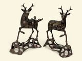 pair of bronze sculptures of a deer and a stag on a stand