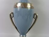 un vase bleu à bord doré posé sur un socle