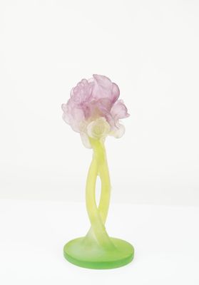 a green vase with a pink flower on a green base
