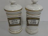 pair of white ceramic jars with black and gold labels on them