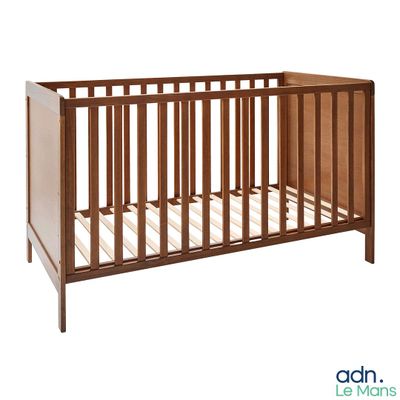 Le lit de bébé est en bois et est équipé d'un matelas blanc.