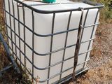 a large container sitting on the ground next to a wooden fence