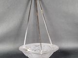 an image of a glass bowl hanging from a metal hook on a gray background