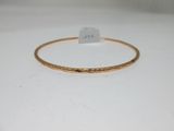 gros plan d'un bracelet en or sur une surface blanche