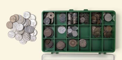 une boîte verte remplie de nombreuses pièces, à côté d'un tas de pièces