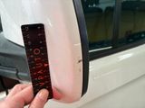 a person holding a ruler in front of a car