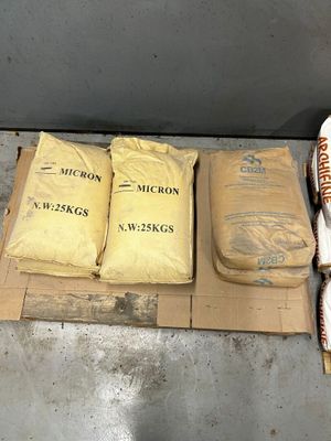 several bags of rice sitting on top of a cardboard box on a floor