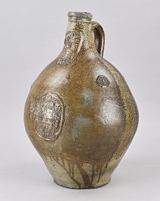 an old stoneware jug with a lion head on it