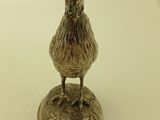 a small silver bird that is on top of a plate