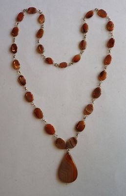 a close up of a necklace with a tear shaped pendant on it