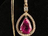 a pink stone and diamond pendant on a gold chain