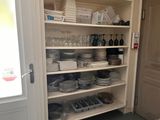 shelves filled with dishes and glasses in a kitchen with a door open