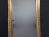 un miroir au cadre doré ouvragé posé contre un mur noir