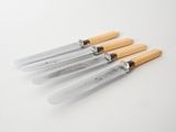 four knives are lined up on a white surface with a wooden handle