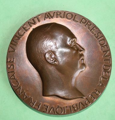 a bronze medal with a man ' s face on it