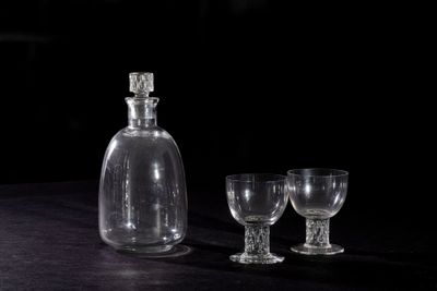 two empty wine glasses and a decanter on a table