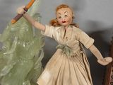 a doll that is holding a tennis racquet next to a clock