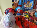 a lot of children ' s backpacks and hats on the bed
