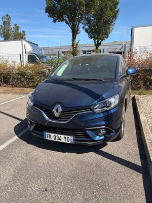 une voiture noire garée dans un parking à côté d'un bâtiment