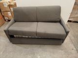 the couch is in a warehouse with boxes and boxes in the background